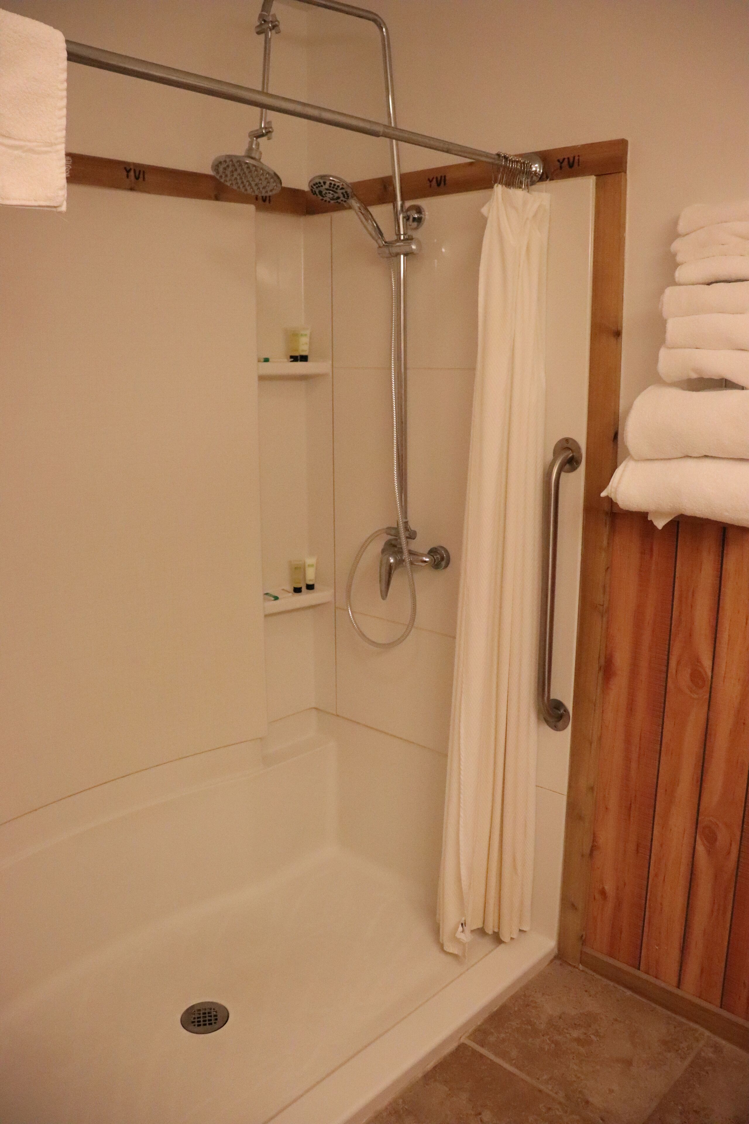 Een douche met houten frame, een handgreep en een handdoekhouder met opgevouwen handdoeken.