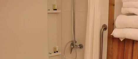 Een douche met houten frame, een handgreep en een handdoekhouder met opgevouwen handdoeken.