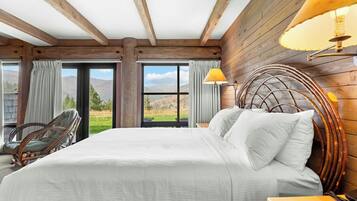 Un dormitorio con una cama grande, una silla, una lámpara y vistas al exterior.
