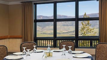 A dining room with a table set for six, large windows with a mountain view, and a view of the countryside.