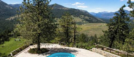 A swimming pool with a view of mountains and a grassy area.