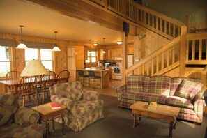 A cozy cabin interior with a dining area, two sofas, a kitchen, and a staircase. - Sun Mountain Lodge (Winthrop)