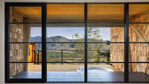 A room with large windows, a hot tub, and a view of mountains. - Sun Mountain Lodge (Winthrop)