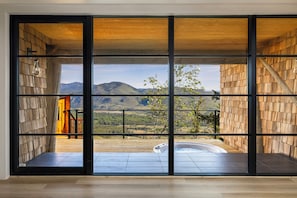 Ein Zimmer mit großen Fenstern, einer Whirlpool-Badewanne und Blick auf Berge.