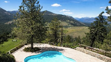 A swimming pool with a view of mountains and a grassy area.