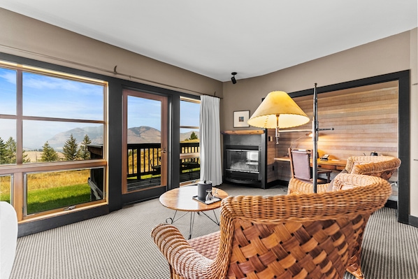 A modern room with large windows, wicker furniture, a fireplace, and a view of the outdoors. - Sun Mountain Lodge (Winthrop)