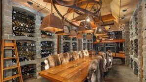 A wine cellar with wooden racks, a long dining table, and fur-covered chairs. - Sun Mountain Lodge (Winthrop)