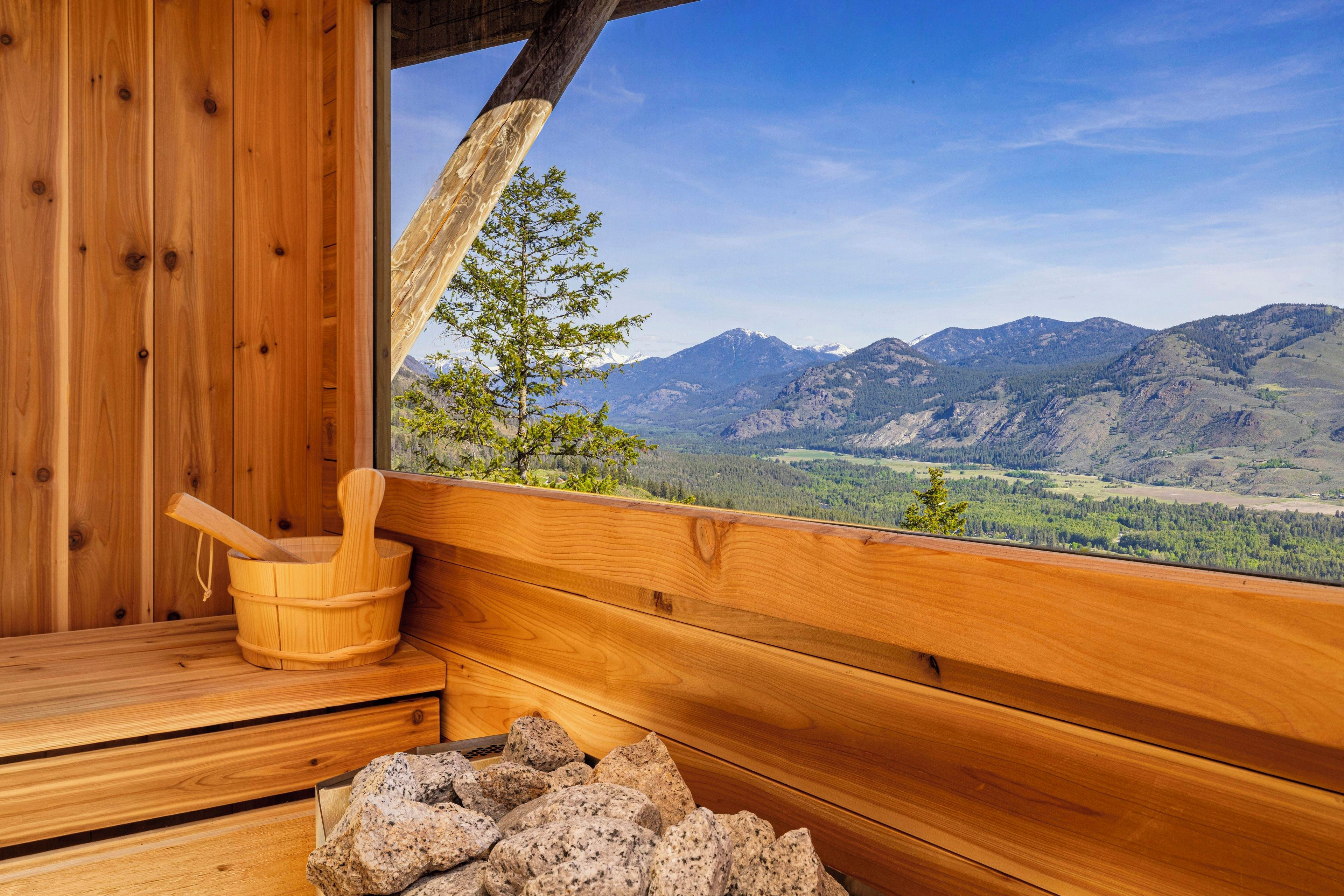 A wooden cabin with a sauna, a wooden bucket, and a pile of rocks.