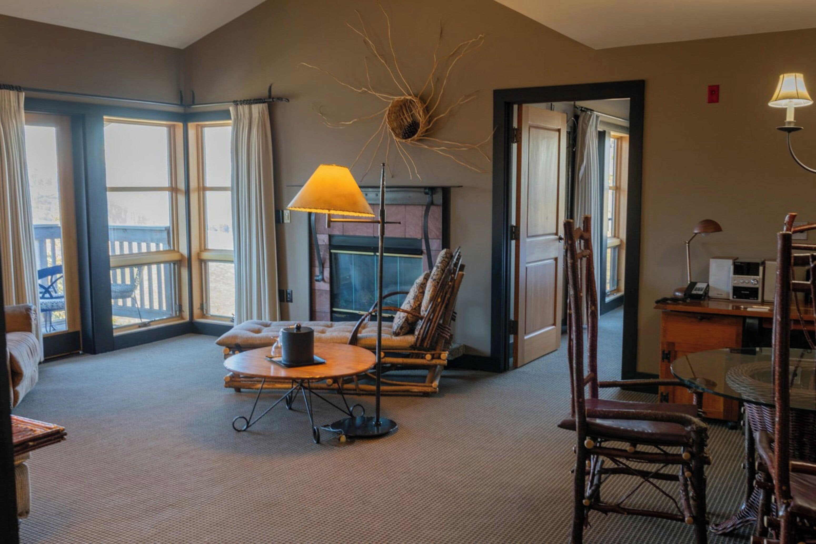 A spacious room with a fireplace, a dining table, a sofa, and a chair.
