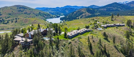 Un complexe hôtelier comprenant plusieurs bâtiments, une piscine et un lac entouré de montagnes.