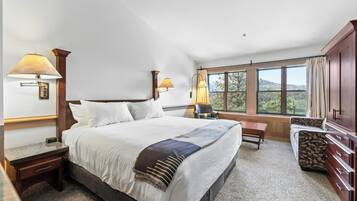 Een hotelkamer met een groot bed, twee bedlampen, een raam met uitzicht, een bureau en een stoel.