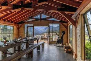 A wooden cabin interior with a dining area, large windows, and a wood stove. - Sun Mountain Lodge (Winthrop)