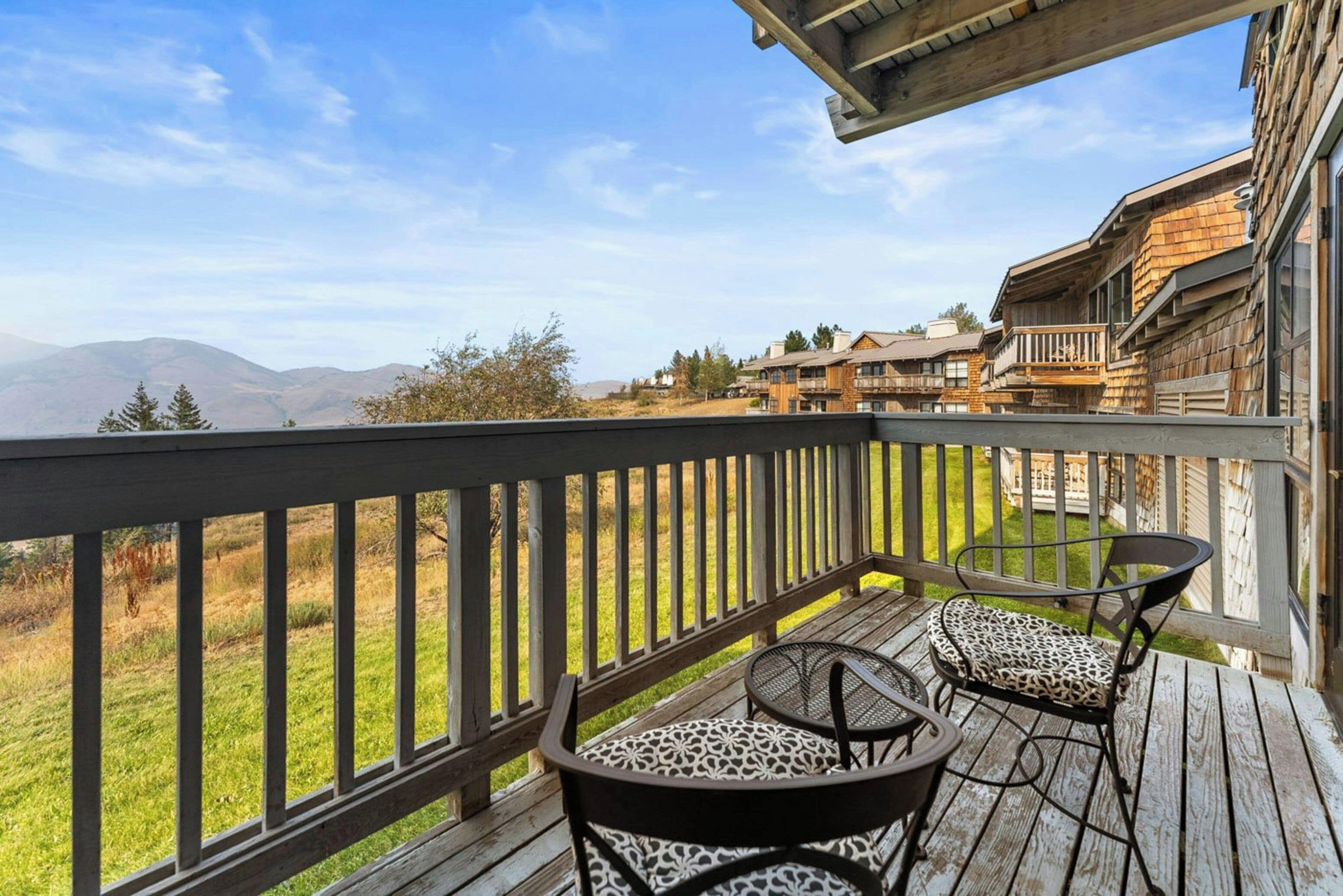 A wooden deck with outdoor furniture, overlooking a mountainous landscape.
