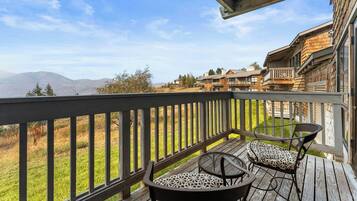 A wooden deck with outdoor furniture, overlooking a mountainous landscape.