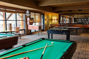 A pool table with a billiard cue and balls, a pool table in the background, and a sign for Sun Mountain Lodge. - Sun Mountain Lodge (Winthrop)
