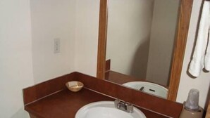 A bathroom with a white sink, a wooden vanity, a mirror, and a towel hanging on the wall. - Willow Springs Motel (Cheney)