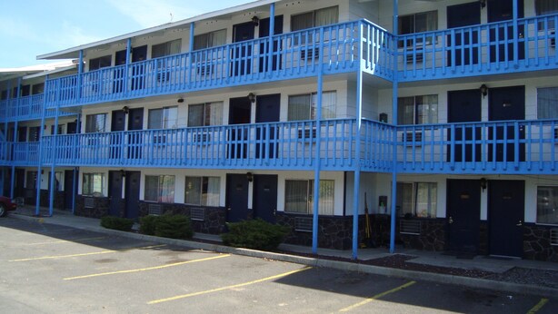 A multi-story motel with blue railings and a parking lot. - Willow Springs Motel (Cheney)