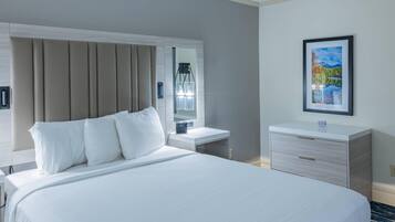 Habitación de hotel con una cama grande, una mesita de noche, un espejo, un cuadro en la pared y un escritorio pequeño.
