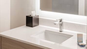 A modern bathroom with a white sink, a black soap dispenser, and a mirror above the sink.