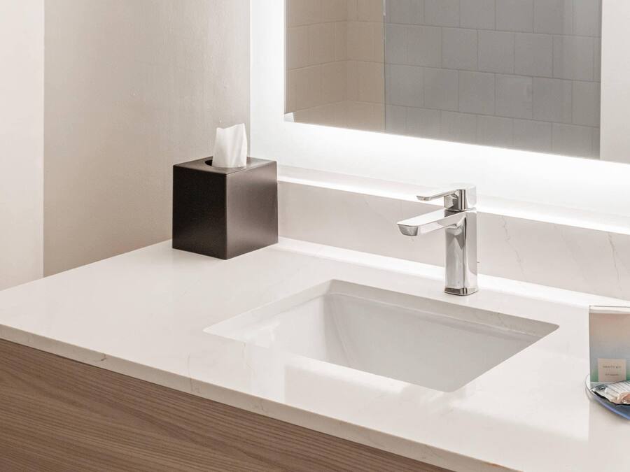 A modern bathroom with a white sink, a black soap dispenser, and a mirror above the sink.