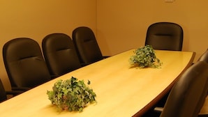 Una sala de conferencias con una mesa larga y seis sillas negras.