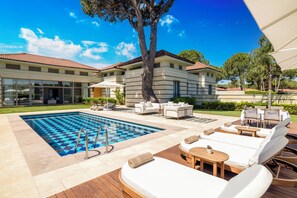 A pool area with lounge chairs and a large tree. - Kempinski Hotel The Dome Belek - All Inclusive (Serik)
