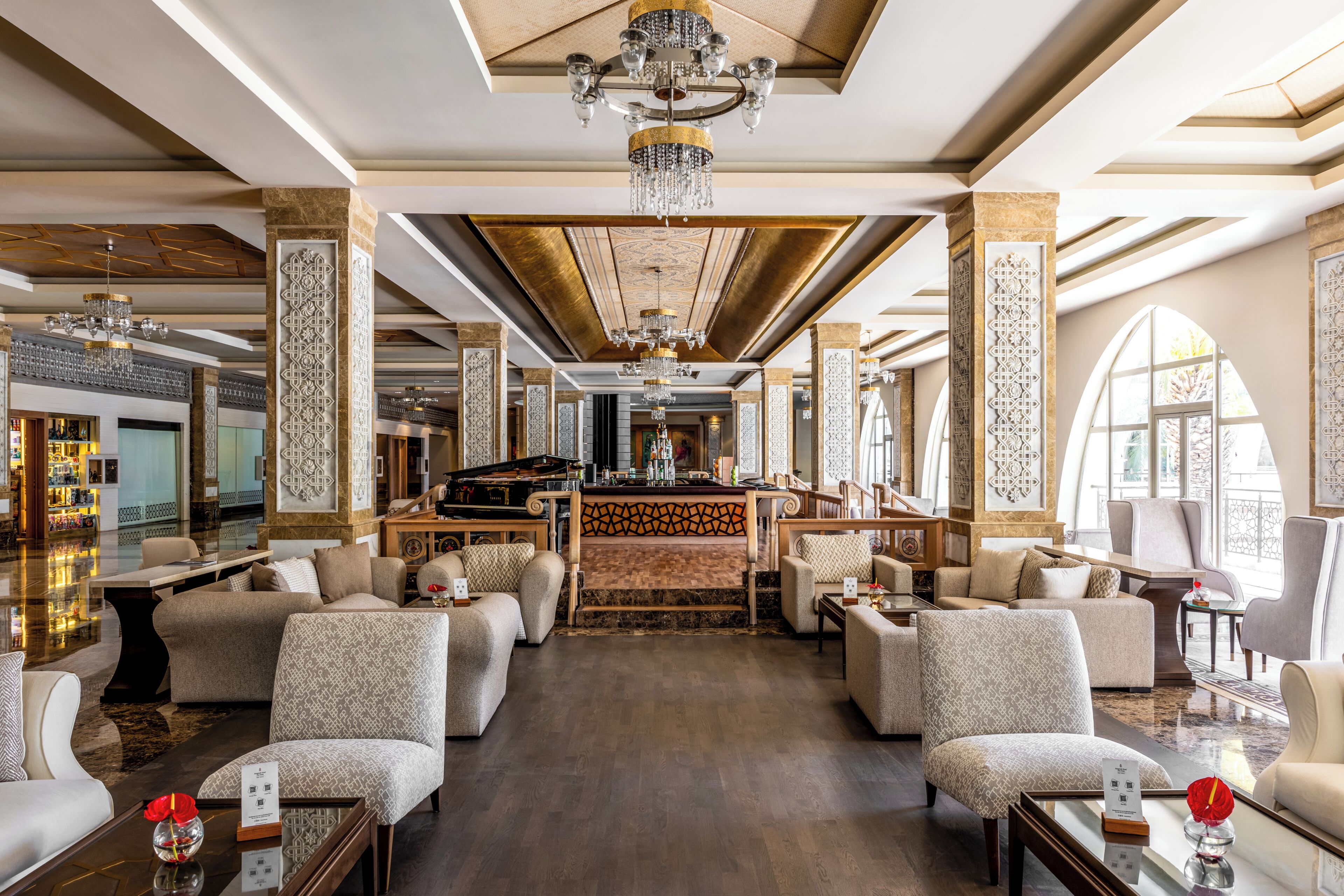Um hall amplo com área de bar, vários espaços de assento e um candelabro.