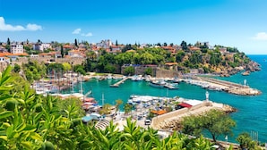 A coastal town with a marina, historic buildings, and a lighthouse. - Kempinski Hotel The Dome Belek - All Inclusive (Serik)