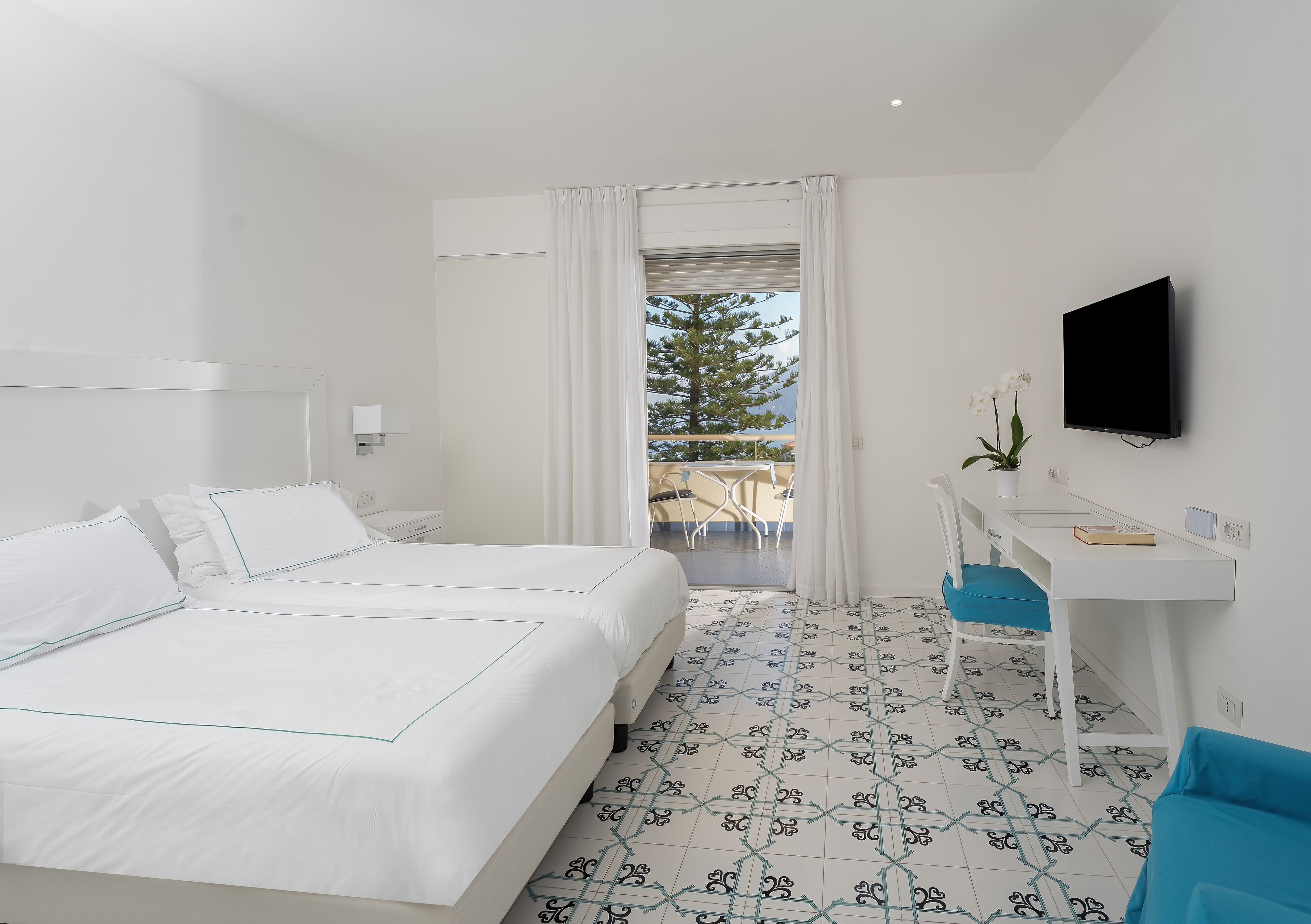 Une chambre d’hôtel équipée d’un lit, d’un bureau, d’une télévision et offrant une vue sur l’extérieur.