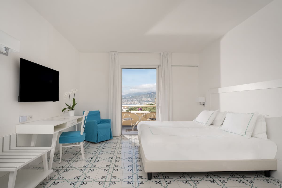 Una habitación de hotel con cama, escritorio, silla y televisor.