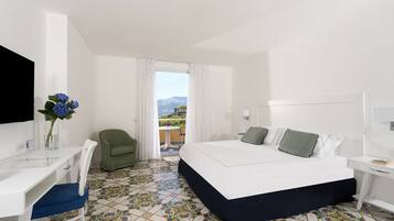 Habitación de hotel con cama, escritorio, silla, televisor y vista al exterior.