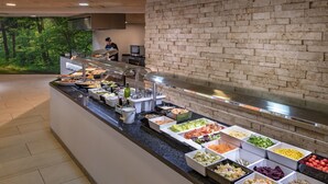 Un bufé con diversos alimentos y un muro de ladrillo al fondo.