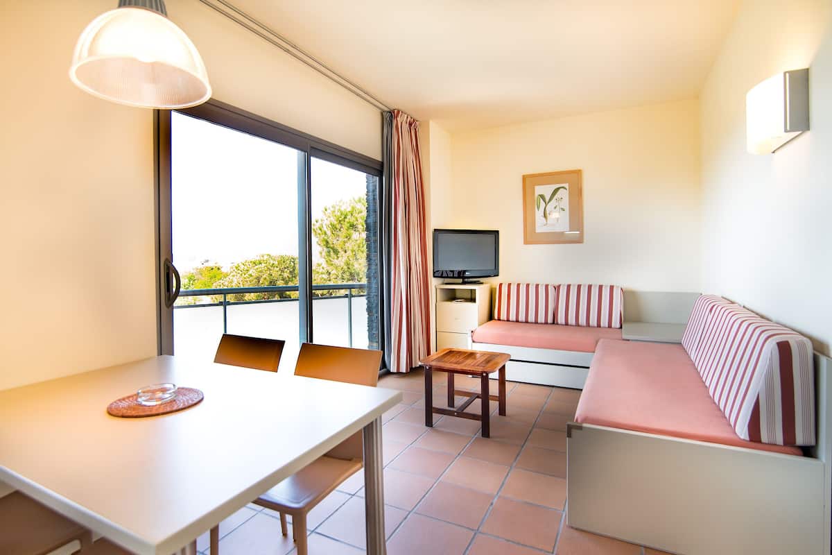 Ein modernes Zimmer mit Esstisch, einer Couch, einem Fernseher und einem Balkon mit Vorhängen.
