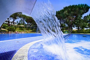 Una piscina al aire libre, sombrillas, sillones reclinables de piscina