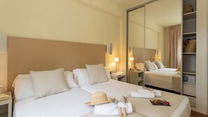 A hotel room with a large bed, a wardrobe, a bedside table, and a mirror.