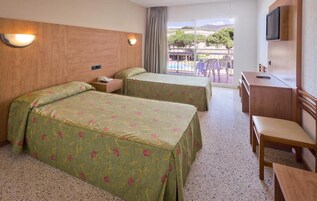 Habitación de hotel con dos camas, un escritorio, una silla y un televisor.