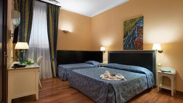 Une chambre d’hôtel avec deux lits, un bureau, une chaise, une télévision et un tableau au mur.