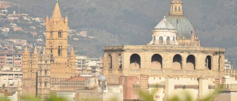 Un edificio histórico con una torre y una cúpula destacadas, rodeado de construcciones urbanas.