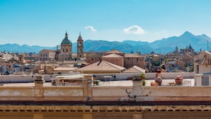 Un edificio histórico con balcones ornamentados y vistas a montañas distantes.