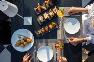 Una mesa lista para una comida, con diversos platos, incluyendo pan, croquetas y una ensalada.