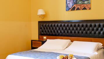 A hotel room with a large bed, a headboard, a nightstand, a lamp, and a painting on the wall.