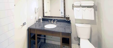 Un baño con lavamanos, espejo y retrete.