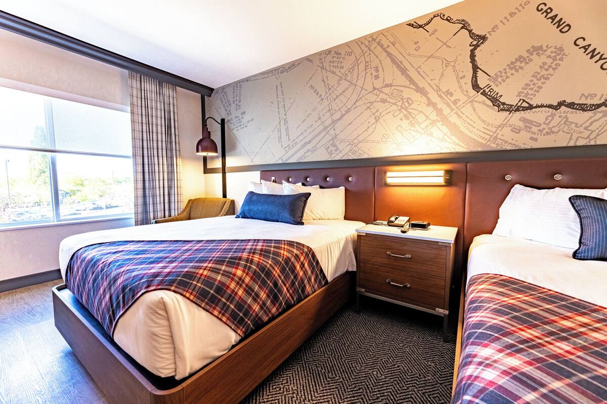 Een hotelkamer met een groot bed, een nachtkastje, een kaart aan de muur en een raam met gordijnen.