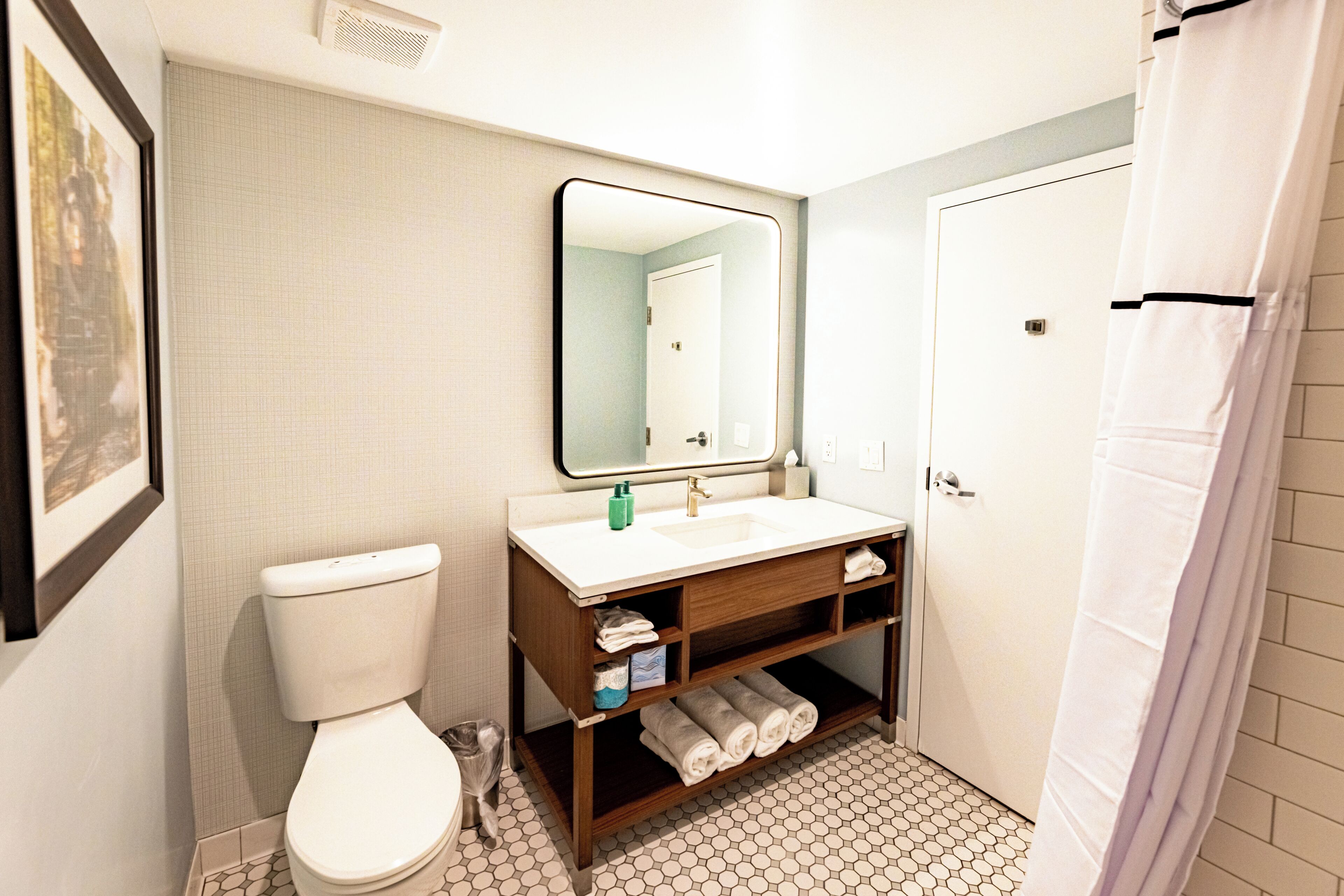 A bathroom with a toilet, sink, mirror, and shower curtain.