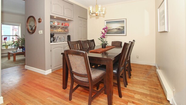 A dining area with a wooden table and chairs, a chandelier, and a painting on the wall. - Gower Guest House (St. John's)