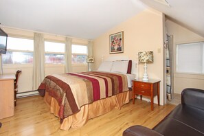 A bedroom with a bed, bedside tables, a desk, and a chair. - Gower Guest House (St. John's)