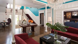 A spacious lobby with a grand staircase, a chandelier, and a red sofa. - Kemble Inn (Lenox)