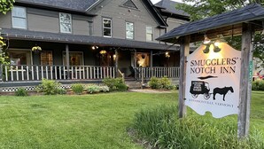 A sign for Smugglers' Notch Inn, featuring a horse-drawn carriage illustration.