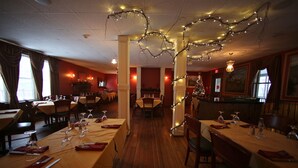 Ein Restaurant mit Holzdielen, gedeckten Tischen und Lichterketten.