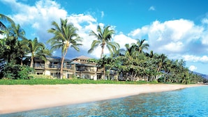 A beachfront hotel with multiple-story buildings, palm trees, and a sandy beach. - Puunoa  - CoralTree Residence Collection (Lahaina)